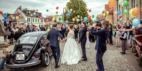 Hochzeitsfotograf Dresden - Die Hochzeitsgäste begrüßen das eintreffende Brautpaar mit bunten Luftballons.