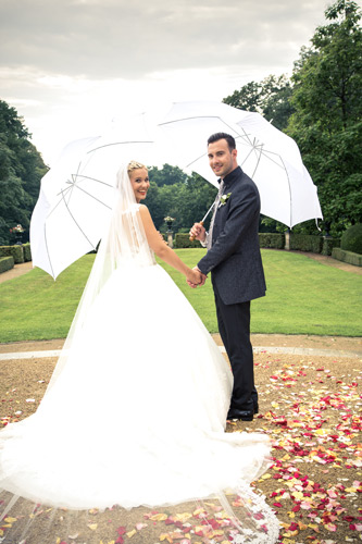 Hochzeitsfotograf Dresden - Das Brautpaar mit Regenschirmen in der Hand, hoffen auf besseres Wetter.
